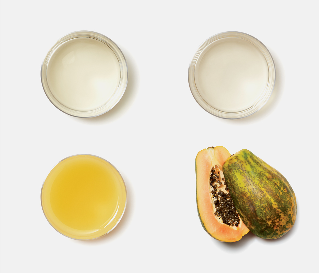 glasses of white wine, white rum and pineapple juice layed out in a sqaure with a halved papaya making up the fourth corner. 