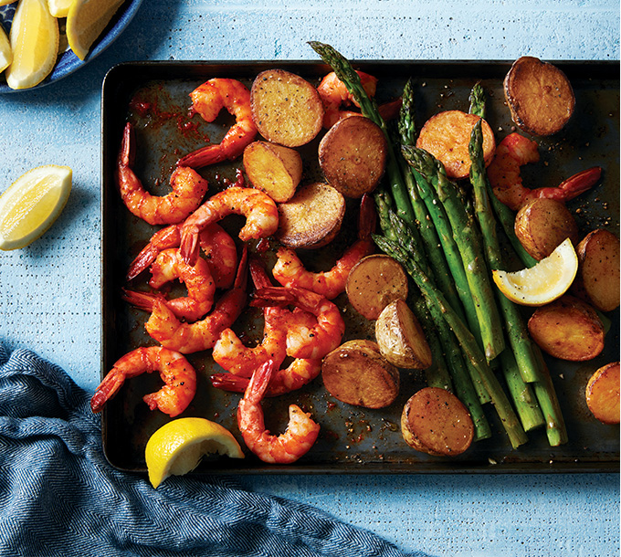 Crevettes et pommes de terre à la harissa et asperges sur plaque à pâtisserie