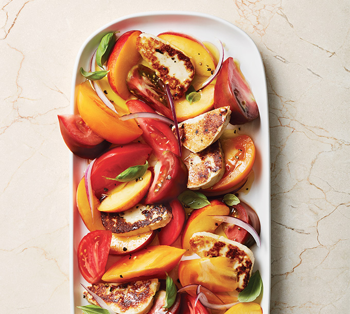 Salade de tomates et de nectarines garnie de halloumi poêlé et de basilic