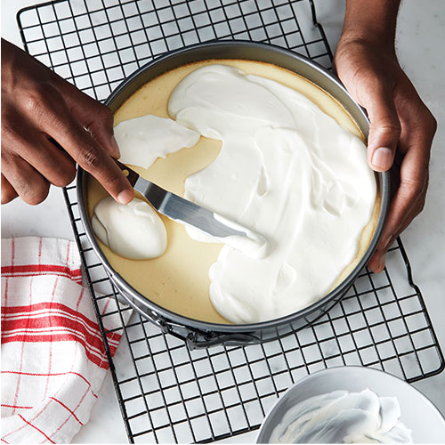 image of topping being spread over baked cheesecake in pan