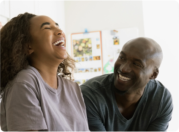 Deux membres de la famille rient à la maison, grâce au programme d’aide aux familles qui favorise le bonheur et le soutien au sein du foyer.