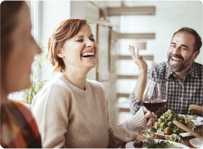 Famille dînant ensemble, riant et buvant du vin, incarnant le modèle tandem travail-loisir.