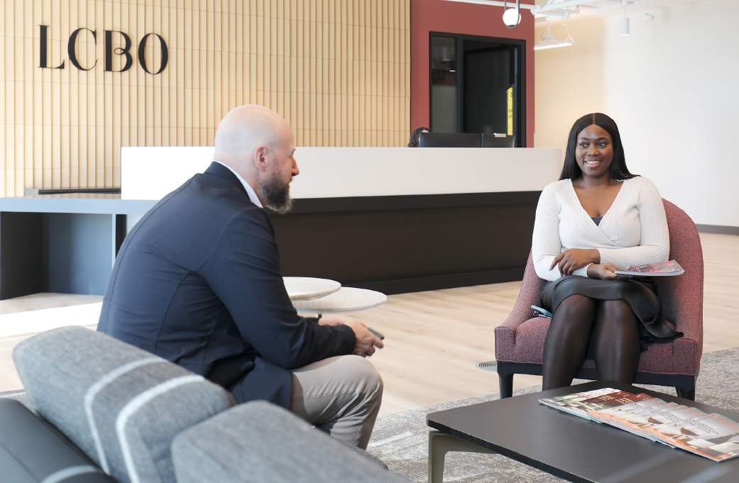 Image d’une employée souriant sur une chaise dans le hall d’entrée du siège social.