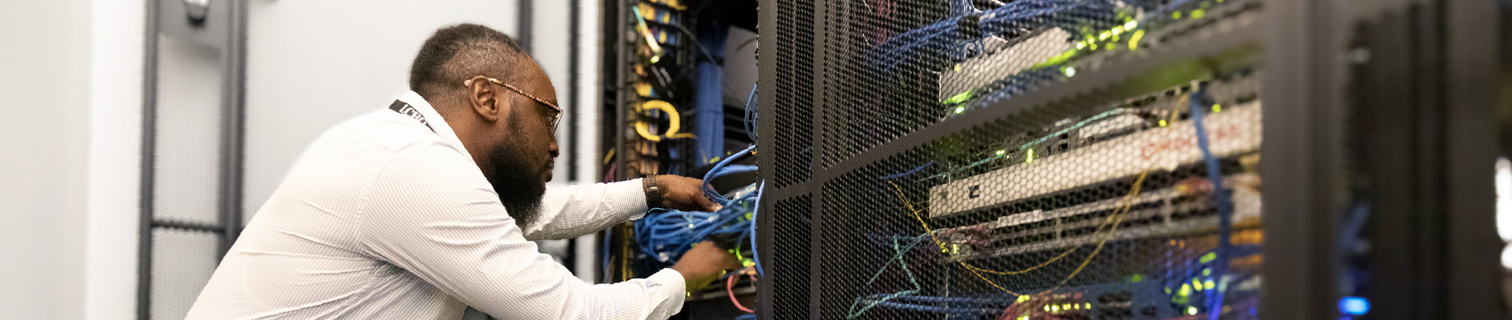 Employé du service informatique travaillant sur une baie de serveurs au siège social de l’entreprise.