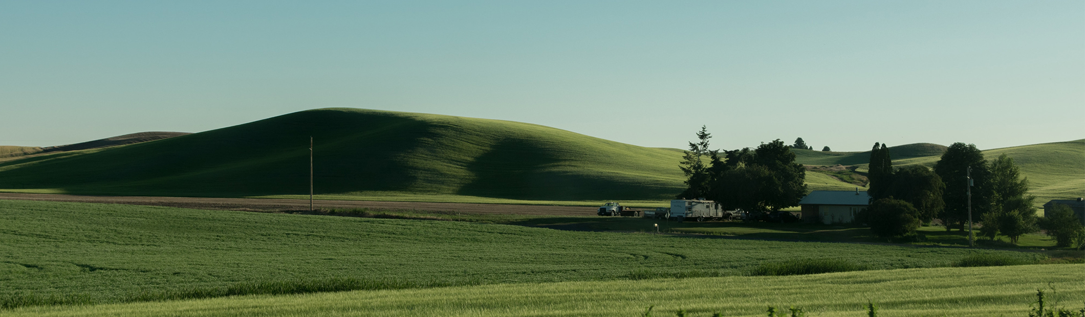 Rolling Green hills of farmland with small white farm house